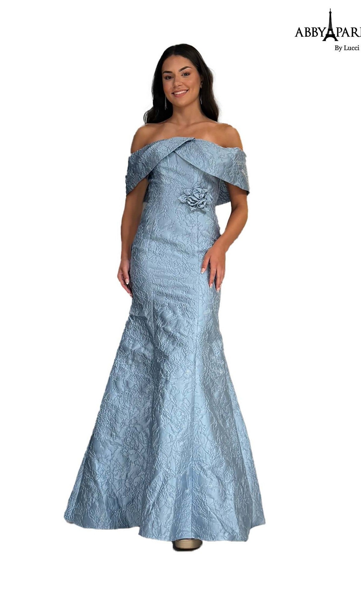 A woman wearing the Abby Paris 96087 long prom dress in dusty blue, featuring an off-the-shoulder brocade design, textured pattern, floor-length hem, and a floral waist detail.
